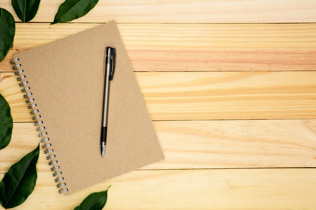 Un libro con hojas verdes en mesa de madera.