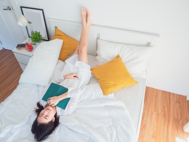 Libro de lectura asiático de la mujer en cama por la mañana