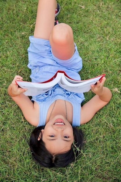 Libro de lectura asiático de la niña en el parque