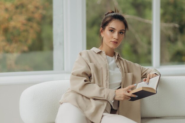 Libro de lectura de chica atractiva en el sofá en casa