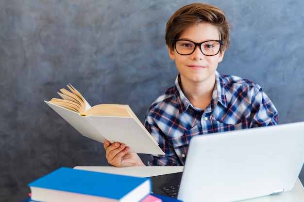 Libro de lectura de chico adolescente y uso portátil en casa