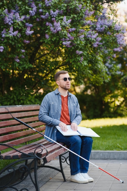 Libro de lectura ciego en un banco en el parque