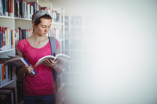 Foto libro de lectura de colegiala atento en biblioteca