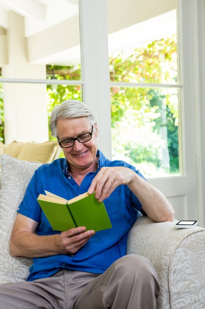 Libro de lectura feliz del hombre mayor en casa