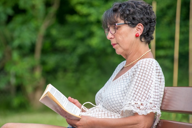 Libro de lectura hermosa mujer senior en el jardín