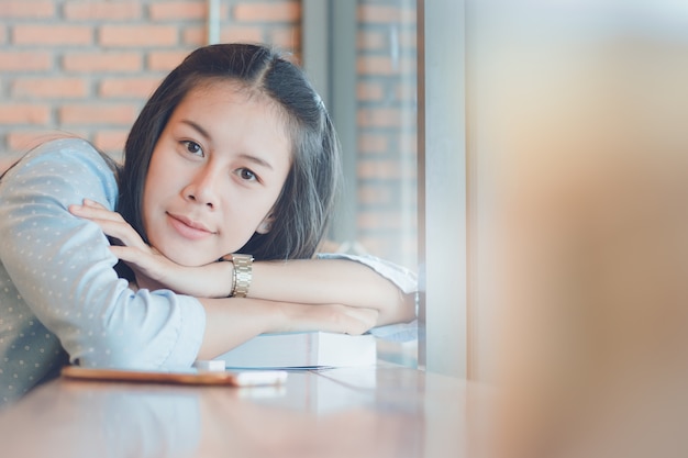 El libro de lectura hermoso de la muchacha de Asia con se relaja en cafetería.