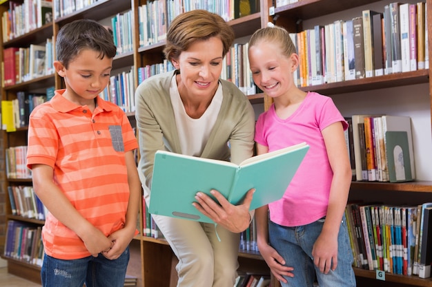 Libro de lectura del maestro con los alumnos en la biblioteca