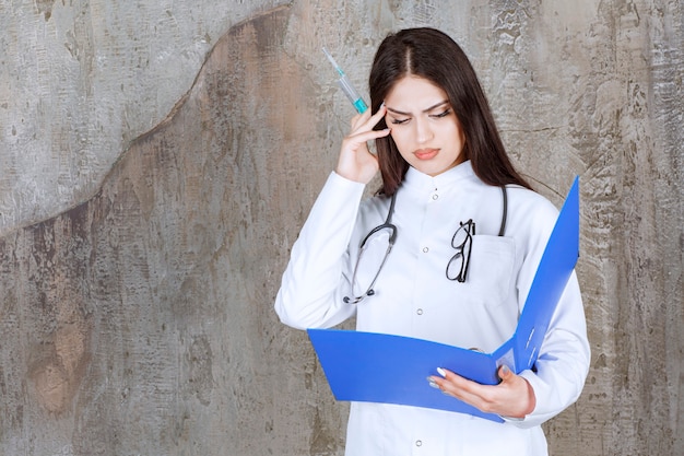 Libro de lectura médico pensativo mientras mantiene la inyección