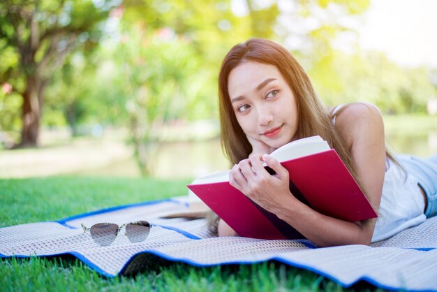 Libro de lectura de mujer asiática sola en el parque el día de la primavera. Relax y recreación. Actividad al aire libre y estilo de vida en vacaciones.