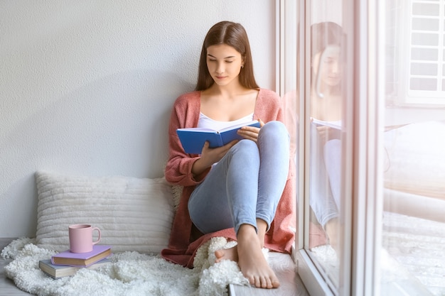 Libro de lectura de mujer joven en casa