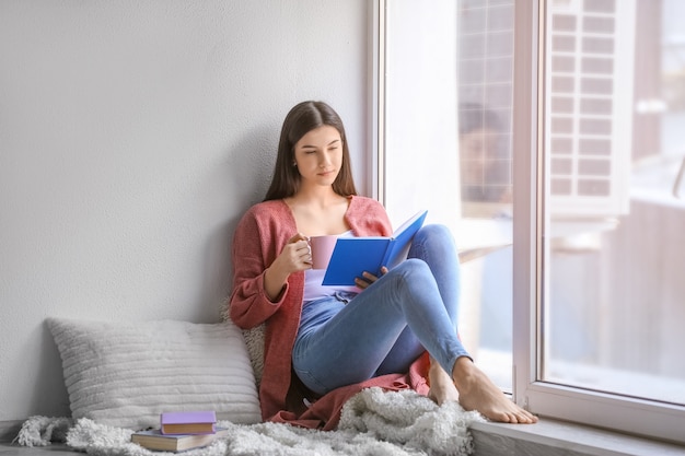 Libro de lectura de mujer joven en casa