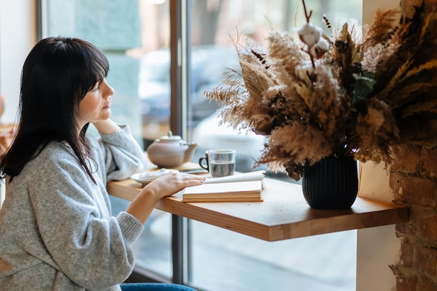 Libro de lectura de mujer sonriente en la cafetería.