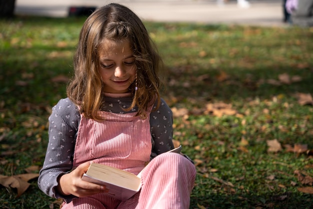 Libro de lectura de niña en el parque