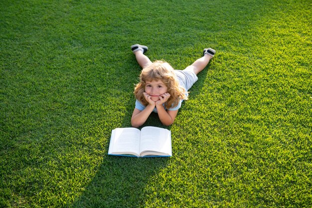 Libro de lectura del niño encantador lindo fuera del libro de lectura del niño en el parque