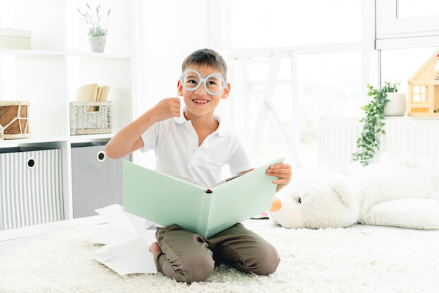 Libro de lectura de niño feliz con gafas