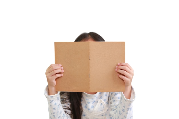 Libro de lectura del niño de la niña caucásica sobre el fondo blanco. Niño sosteniendo la portada del libro marrón ocultar su rostro - Trazado de recorte