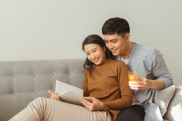 Libro de lectura de pareja atractiva en el sofá en casa en la sala de estar