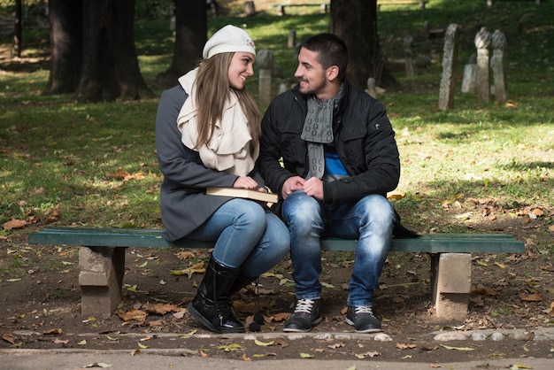 Libro de lectura relajado pareja joven en un banco del parque