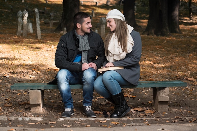 Libro de lectura relajado pareja joven en un banco del parque