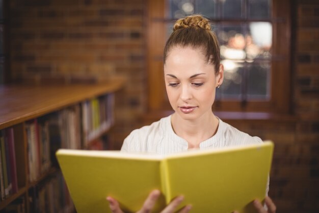 Libro de lectura rubio del profesor en la biblioteca