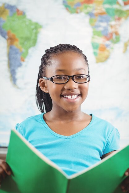 Libro de lectura sonriente del alumno en un aula