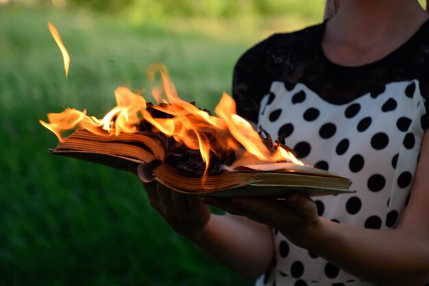 Foto libro en llamas en las manos libros en llamas en el bosque