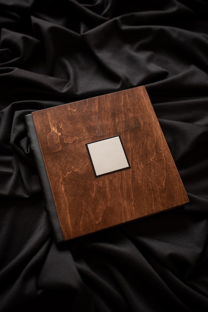 Libro de madera con una placa de identificación sobre un fondo de tela negra.