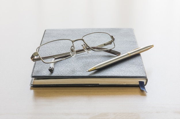 Libro negro con gafas y pluma