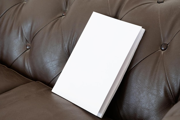 Libro con portada en blanco en un sofá de cuero