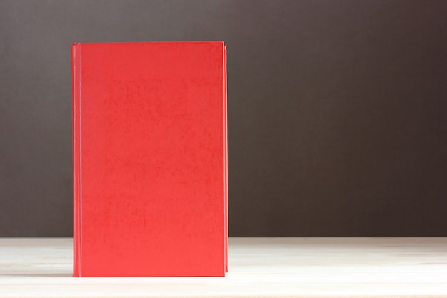 Libro rojo con una cubierta en blanco sobre la mesa.