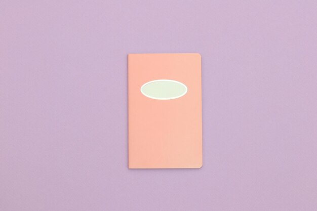 Un libro rosa con un óvalo en el medio sobre un fondo morado.