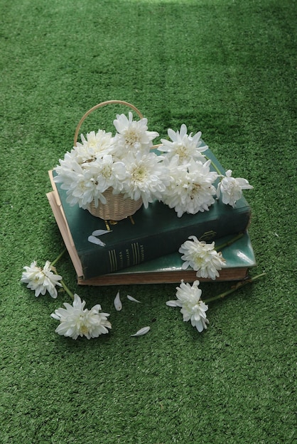 Un libro sobre una alfombra verde con una cesta de flores encima.