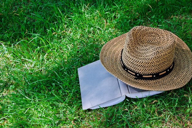 Libro y sombrero de paja sobre hierba