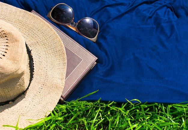 libro de sombreros de verano y gafas de sol sobre la hierba verde Concepto para las vacaciones de verano