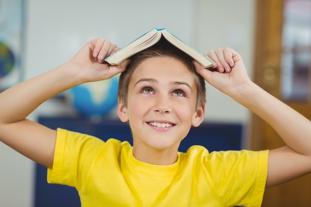 Libro sonriente de la explotación del alumno en la cabeza en un aula