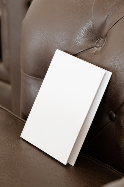 Libro con tapa en blanco en el sofá de cuero.