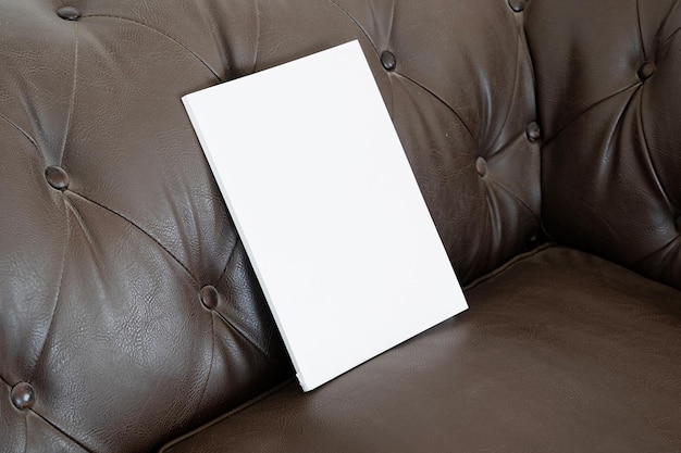 Libro con tapa en blanco en el sofá de cuero.