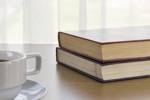 Libro y taza de café sobre una mesa de madera