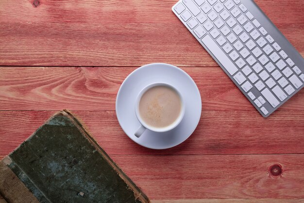 Libro viejo, computadora y café en una mesa de madera