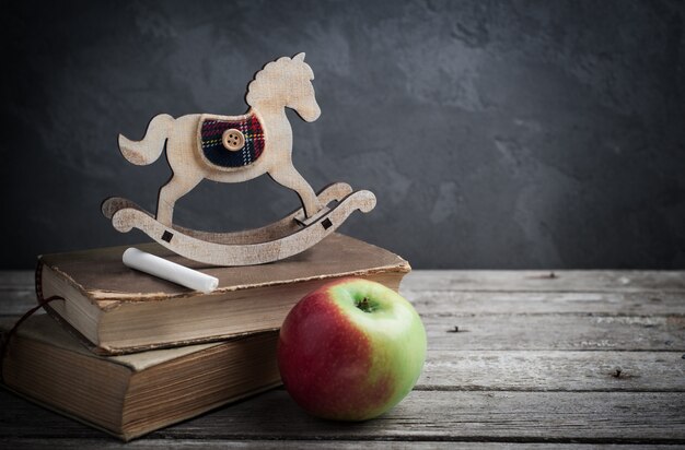 Libros antiguos y caballo de juguete de madera.