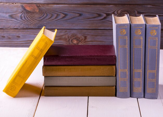 Foto libros antiguos colocados sobre una mesa de madera blanca