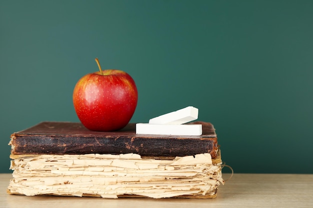 Libros antiguos manzana y tiza sobre fondo de pizarra