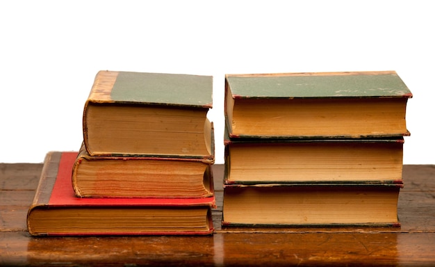 Libros antiguos sobre mesa de madera con fondo blanco.