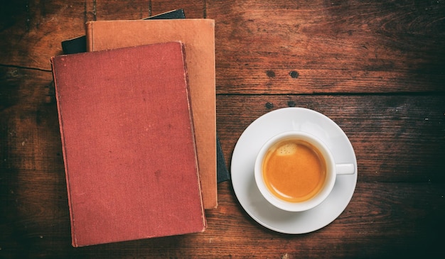 Libros antiguos y una taza de café sobre fondo de madera