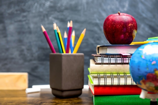 Libros, artículos de papelería y material educativo en el escritorio de madera en el aula