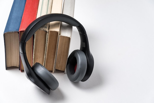 Libros y auriculares estéreo sobre un fondo blanco Escuche el concepto de audiolibro de libros