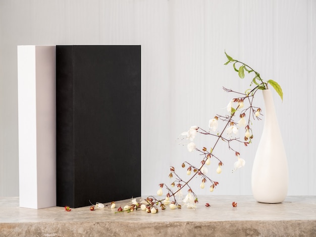 Los libros en blanco y negro se burlan y la hermosa flor de clerodendron asintiendo con la cabeza en un jarrón moderno en una mesa de hormigón