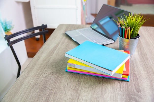 Libros y computadora en mesa en la escuela.