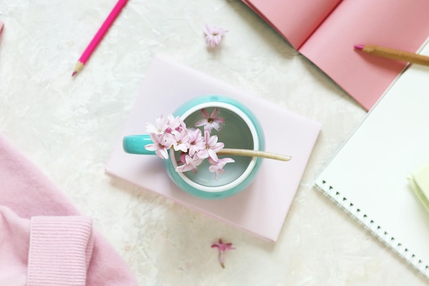 Libros y cuadernos, flores de jacinto rosa, suéter rosa de cachemira, una taza de agua.