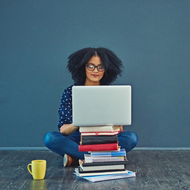 Libros de educación y computadora portátil del estudiante por la pared investigación y escritura de información para la asignación académica Mockup persona femenina y digital para el estudio de conexión o curso en línea para maestría